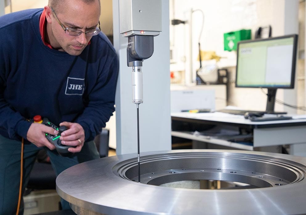An inspector measuring a large machined ring on a coordinate measuring machine