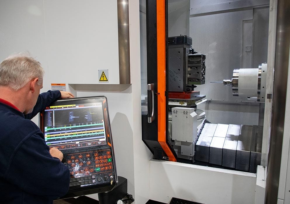 An operator programming a mill-turn machine at its control